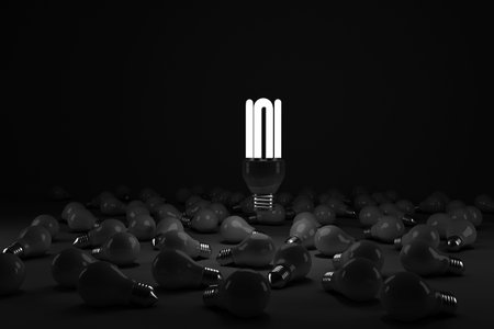 Lit energy efficient lightbulb over bulbs against black backgroundの写真素材