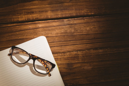 Reading glasses on book over wooden tableの写真素材