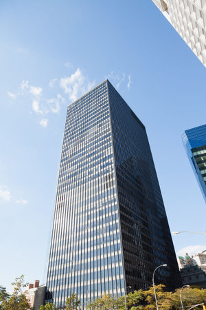 Flat street scene featuring office tower rising and reflecting clouds, showing streetlamp, trees. Skyscraper, urban, modern, architecture, cityscape, reflection, metropolitanの写真素材
