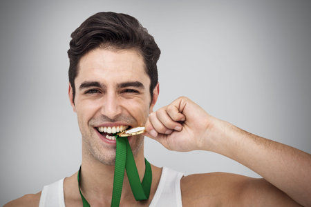 Portrait of happy male athlete with medals against gray backgroundの写真素材