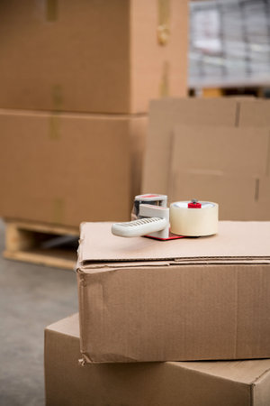 Close-up of packaging equipment on cardboard box in warehouseの写真素材