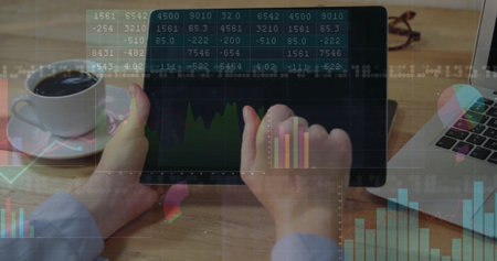 Analyst analyzing financial charts on digital tablet at wooden desk, showing laptop and coffee cup....