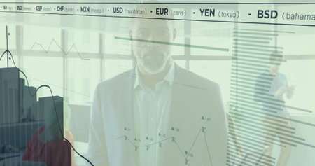 Standing African American man analyzing digital charts on office glass wall showing currency ticker....