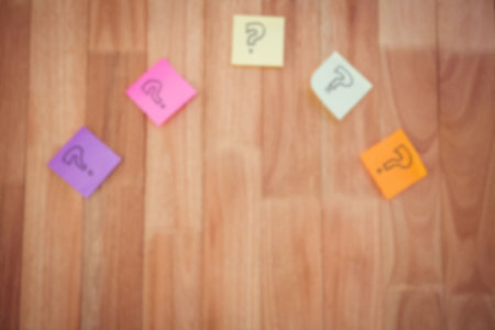 Overhead view of colorful sticky notes with question marks on hardwood floorの写真素材