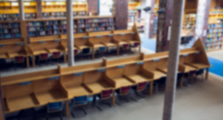 Empty chairs and wooden desks in library