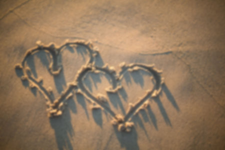 Heart shapes on sand at beach during sunset