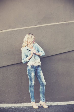 Young woman looking away while standing against wallの写真素材