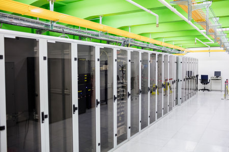 Illustrating flat datacenter switch racks under yellow trays and beams, raised tiles, desk monitors....