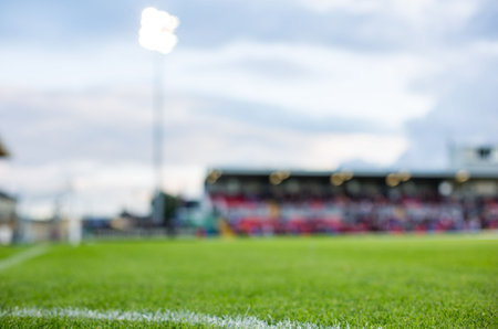 Displaying grass field with white boundary line, featuring stadium seating and floodlight tower. Soccer, sports, outdoor, field, turf, recreation, competitionの写真素材