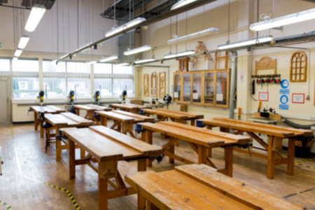 Flat design workshop showing rows of benches with vices and power tools under windows....