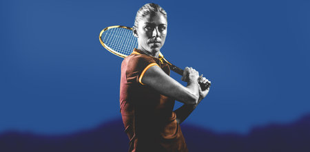 Focused female tennis player holding racket against blue sky