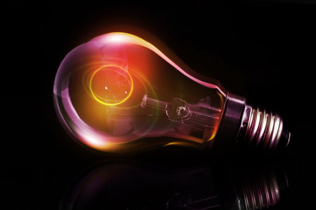Incandescent light bulb is resting on reflective surface in 3D render dark backdrop with warm halos....
