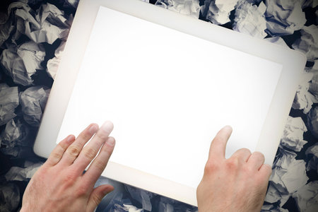 Hands touching tablet screen on crumpled up paper