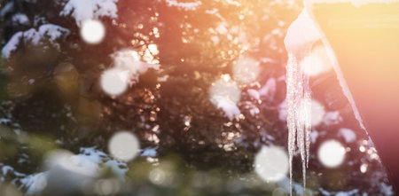 Low angle view of icicle on roof during winter with bokeh in foreground