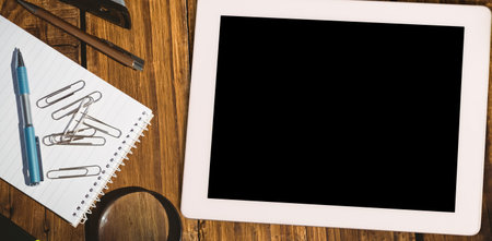 Overhead desk workspace is showcasing flat design tools, with tablet, notebook pen and magnifier....