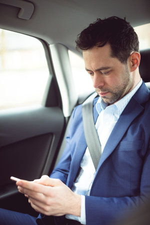 Handsome young man in full suit looking at his smart phone