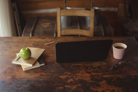 Coffee cup by laptop on wooden table at homeの写真素材