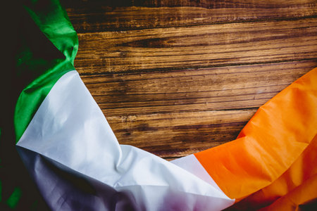 Draped Irish tricolor flag is being shown on rustic wooden plank tabletop in flat design. Patina, heritage, patriotism, vintage, craft, tradition, nationalismの写真素材