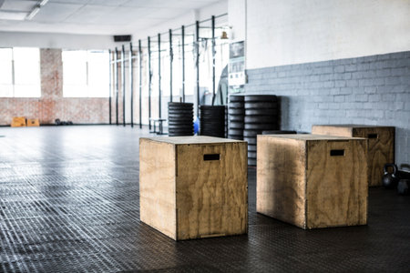 Wooden plyometric box sitting inside flat design gym space, featuring racks, plates, kettlebells. Fitness, gym, workout, strength, training, sport, industrialの写真素材
