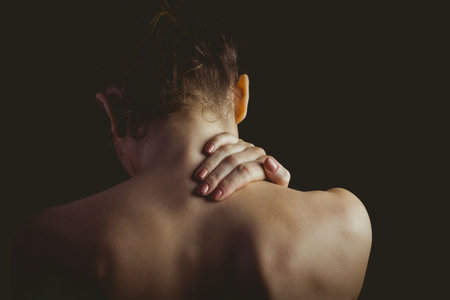Flat illustration showing bare-shouldered woman with hand on neck in studio highlighting contours. Portrait, beauty, elegance, femininity, dramatic, moody, silhouetteの写真素材