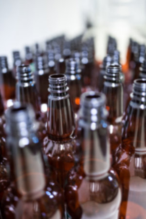 Close-up of beer bottles arranged in row at factory