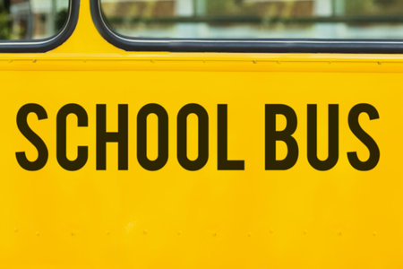 Flat design highlighting side yellow school bus with rectangular windows, black lettering, rivets. Vintage, transportation, vehicle, exterior, cityscape, modal, mobilityの写真素材