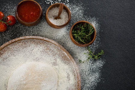 Overhead view of pizza dough with ingredients on table
