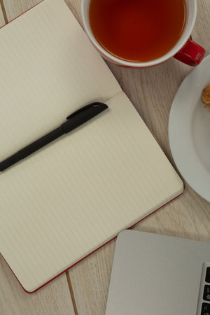 Laptop, lemon tea, croissant and diary on table, Close-up