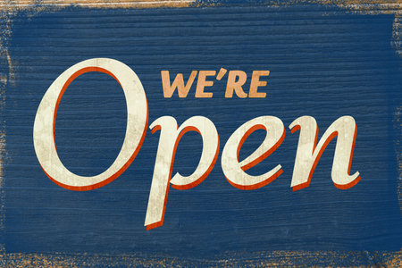 Flat design wooden 'We're Open' sign is showing on weathered blue plank backdrop with peeling paint....