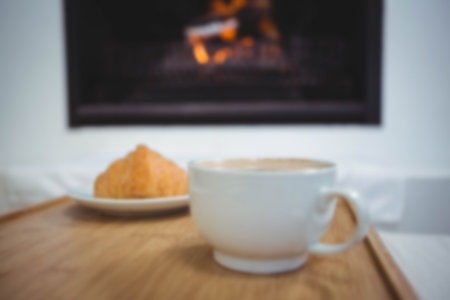 Close up of tea cup by food in plate on table against fireplace at homeの写真素材