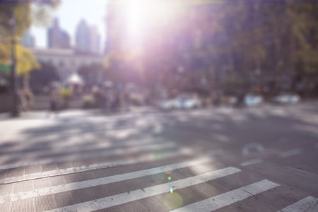 Zebra-striped crosswalk is stretching across sunlit city street with lens flare in flat design. Urban, infrastructure, architecture, transportation, pattern, streetscape, mobilityの写真素材