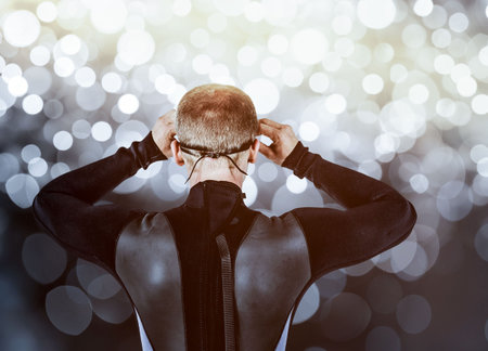 Rear view of swimmer in wetsuit against digitally generated lens flareの写真素材
