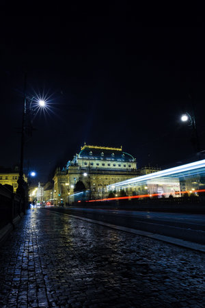 Flat vector is showing illuminated theatre with cobbled street and light trails under street lamps. Historic, urban, nighttime, cinematic, vintage, vibrant, atmosphericの写真素材