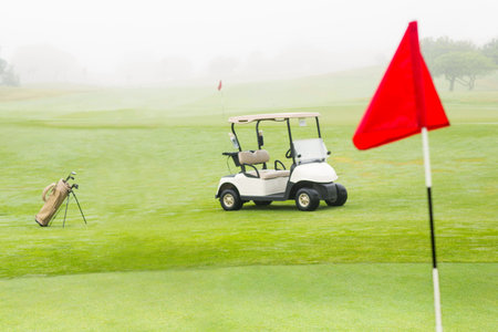 White two-seater golf cart is sitting on misty fairway in vector illustration with bag, red flag. Luxury, recreation, outdoor, landscape, serene, leisure, activityの写真素材