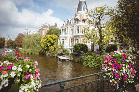 Flat design showing ornate canal house, wrought-iron railing, flower baskets and moored boat. Scenic, historic, picturesque, elegant, tranquil, urban, botanicalの写真素材