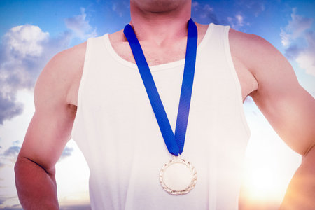 Midsection of young male athlete standing with gold medalの写真素材