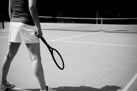 Low section of woman standing with racket on tennis courtの写真素材