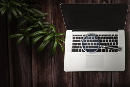 Magnifying glass on a laptop on the tableの写真素材