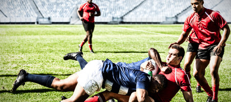 Rugby players tackling each other to win the ball in stadiumの写真素材