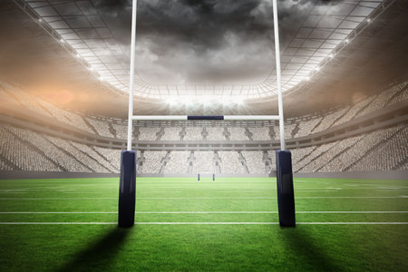 Pair of upright goalposts standing in stadium under curved roof with grass field and floodlights. Stadium, sports, arena, competition, architecture, night, outdoorの写真素材