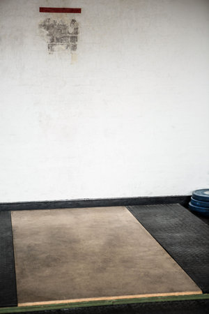 Flat design weightlifting platform is showing wood center with mats, plates, red tape on brick wall. Gym equipment, fitness, training, industrial design, strength, workout space, athleticの写真素材
