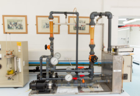Flat design lab bench is featuring fluid mechanics setup with centrifugal pump, grey pipes....