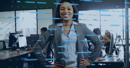 Standing businesswoman projecting confidence in open-plan office, with monitors and data overlay. Professional, technology, teamwork, modern, collaborative, digital, workspaceの写真素材