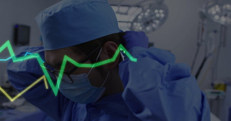 Mature surgeon in blue scrubs adjusting gloves, cap under surgical lights in OR, with ECG overlay....