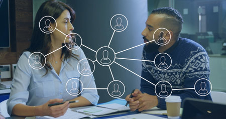 Discussing two executives in business attire taking notes at meeting table, showing network overlay....