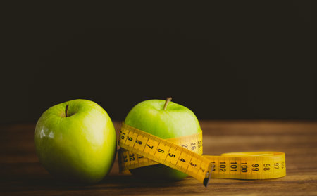Green apples and measuring tape on wooden table