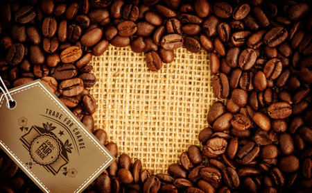 Heart shape with quality tag surrounded by coffee beans over textileの写真素材