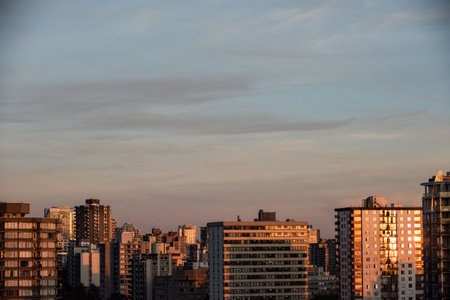 Sunlight falling on buildings in city against sky during sunsetの写真素材