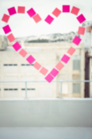 Heart shape made from pink sticky notes on glass window in officeの写真素材