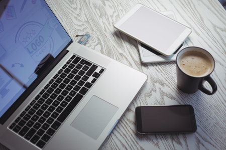 High angle view of various technologies with coffee cup on table in office